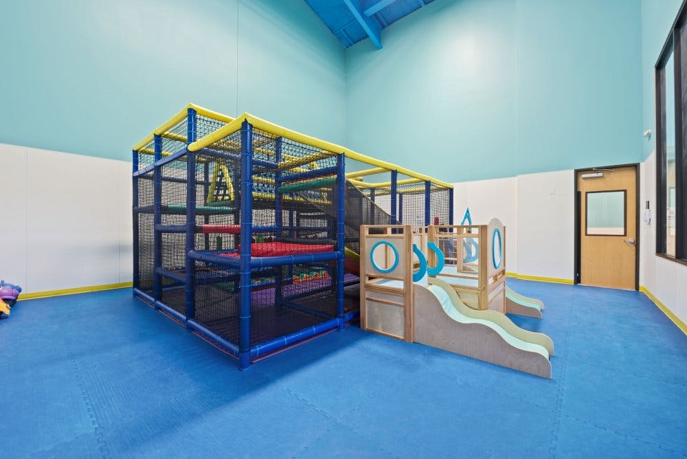 Indoor play area with soft play structure and toddler slides on blue padded floor