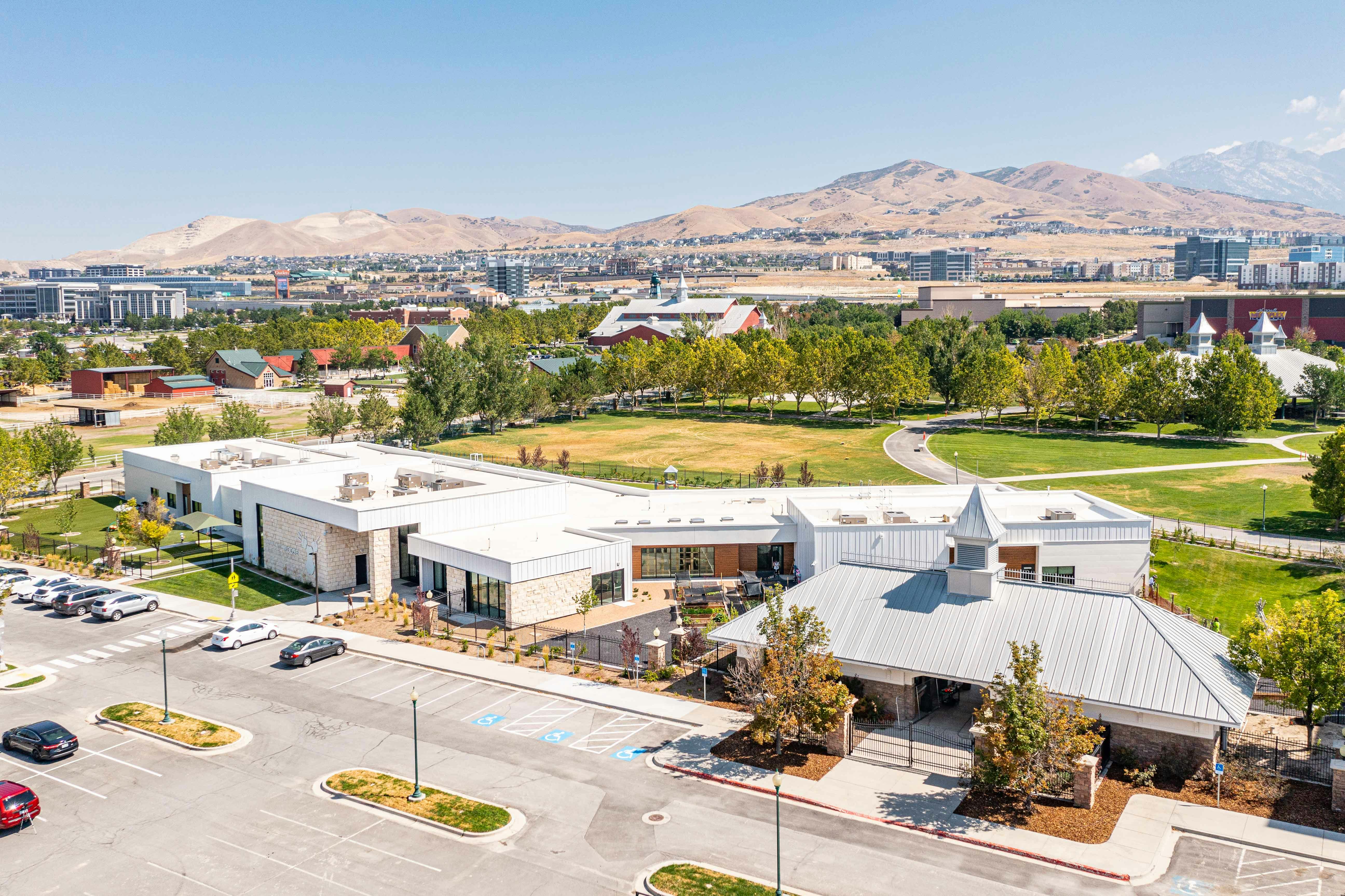 Aerial view of a modern building with a parking lot and mountains in the background