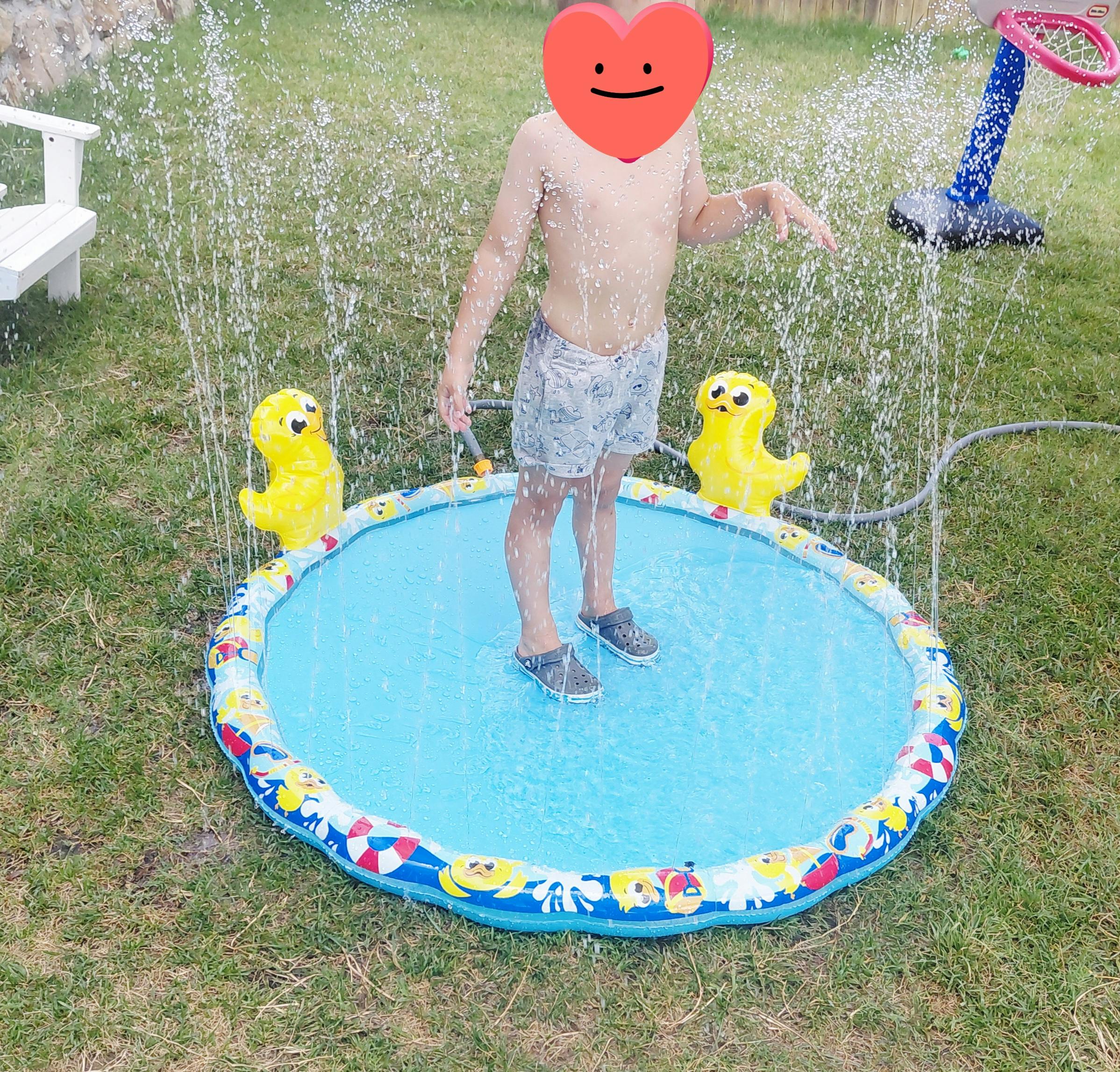 Child playing in a water sprinkler splash pad on a lawn