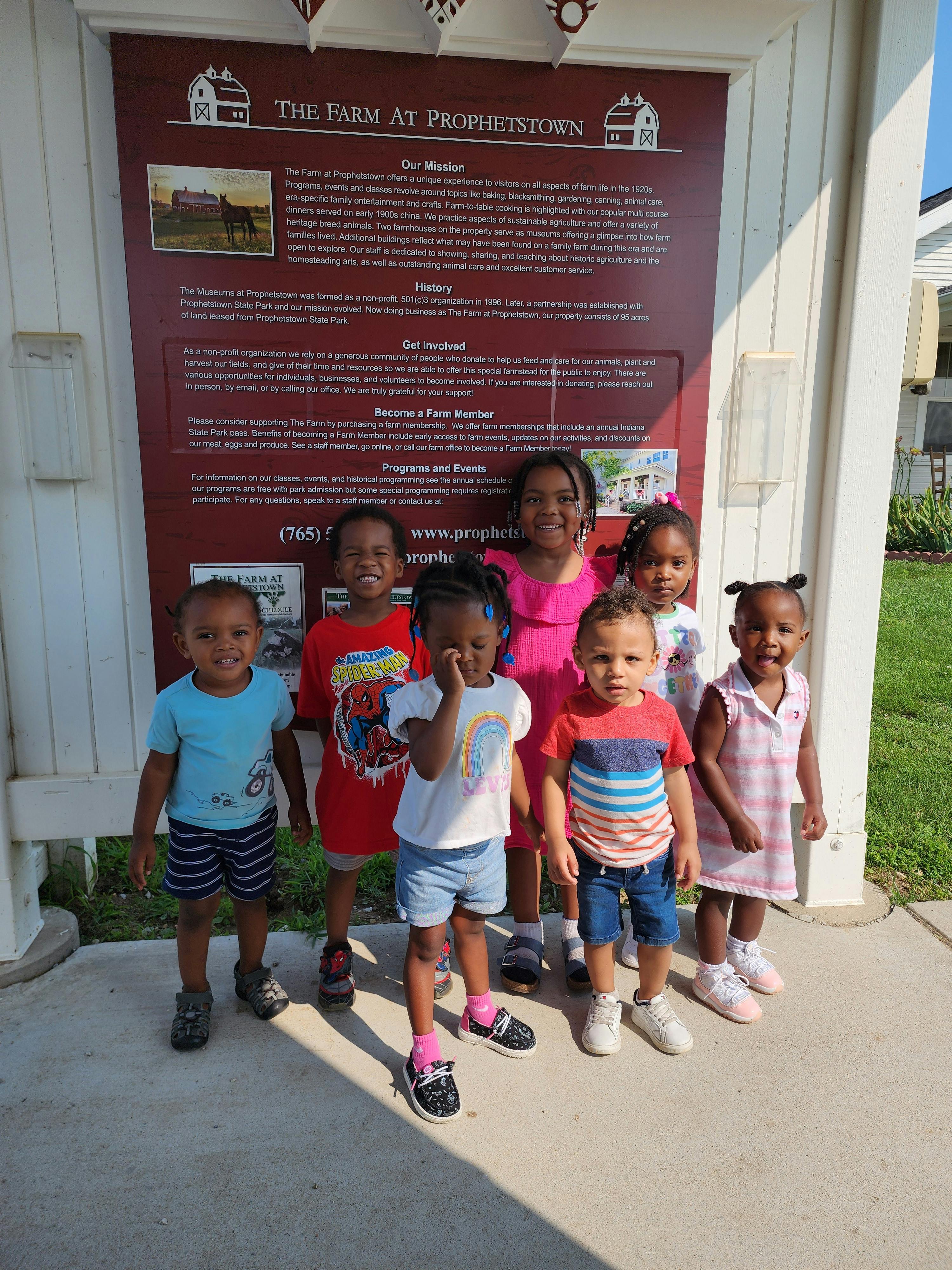 Group of children standing next to a large sign that reads "THE FARM AT PROPHETSTOWN"