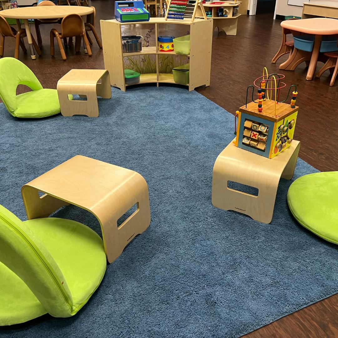 Playroom with small chairs, tables, and toys on a blue rug