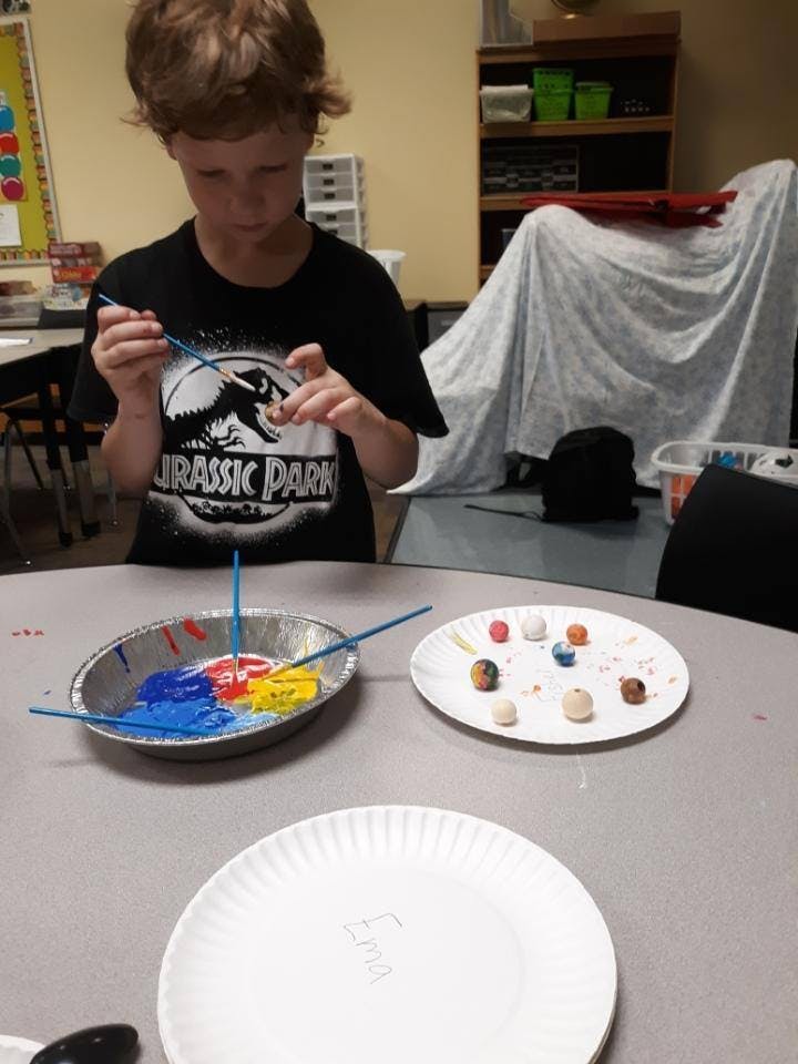 Child painting small objects at a table