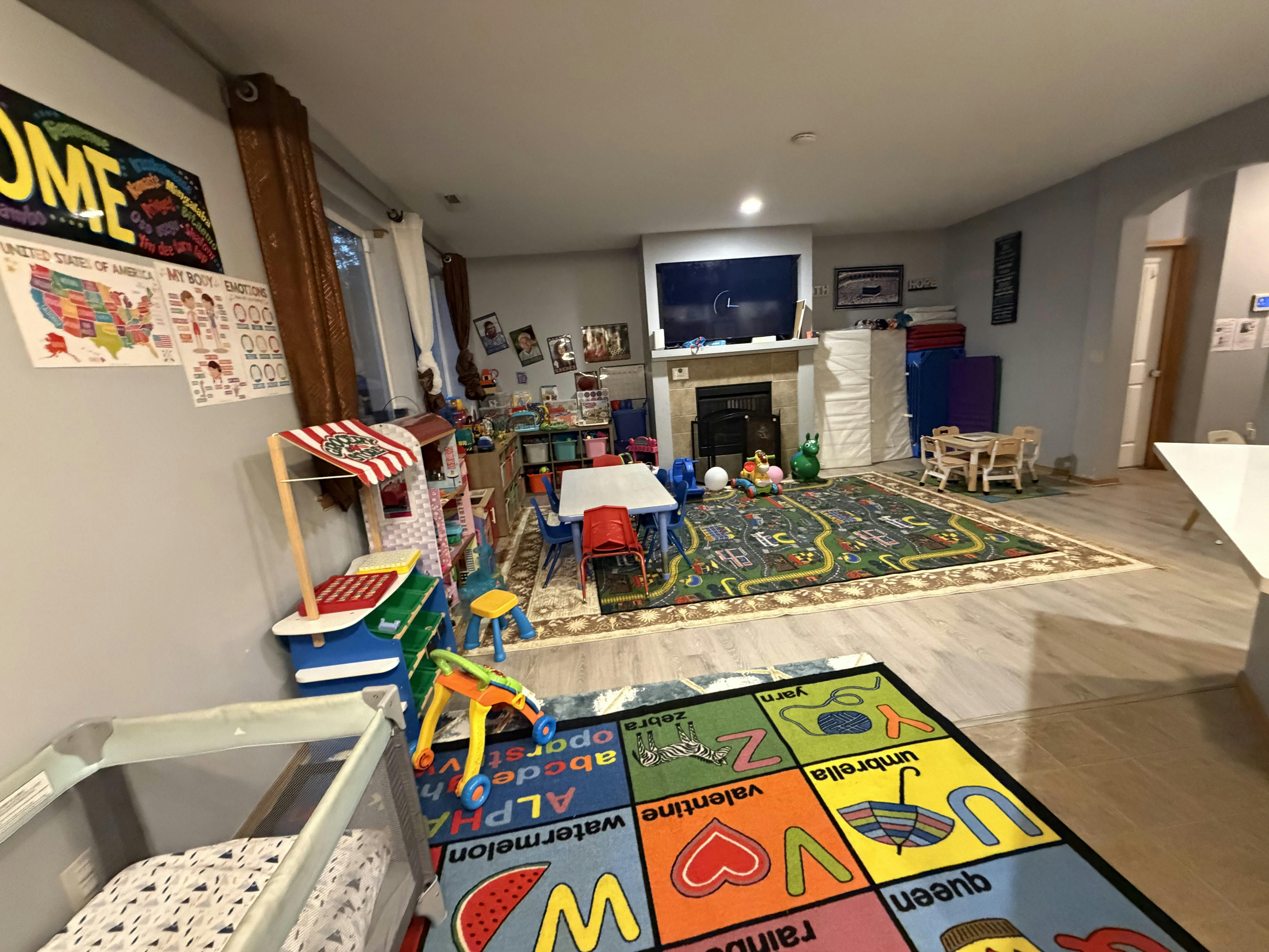 Playroom with children activity tables, a play kitchen, and educational rugs