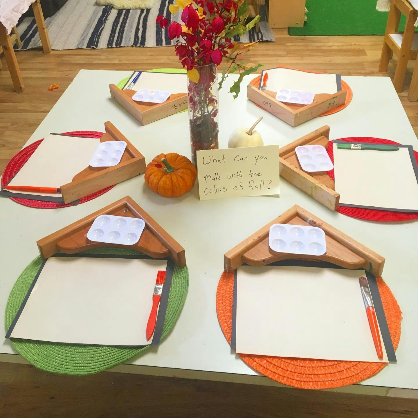 Table set with multiple art stations, each with paper, paint palette, and brush