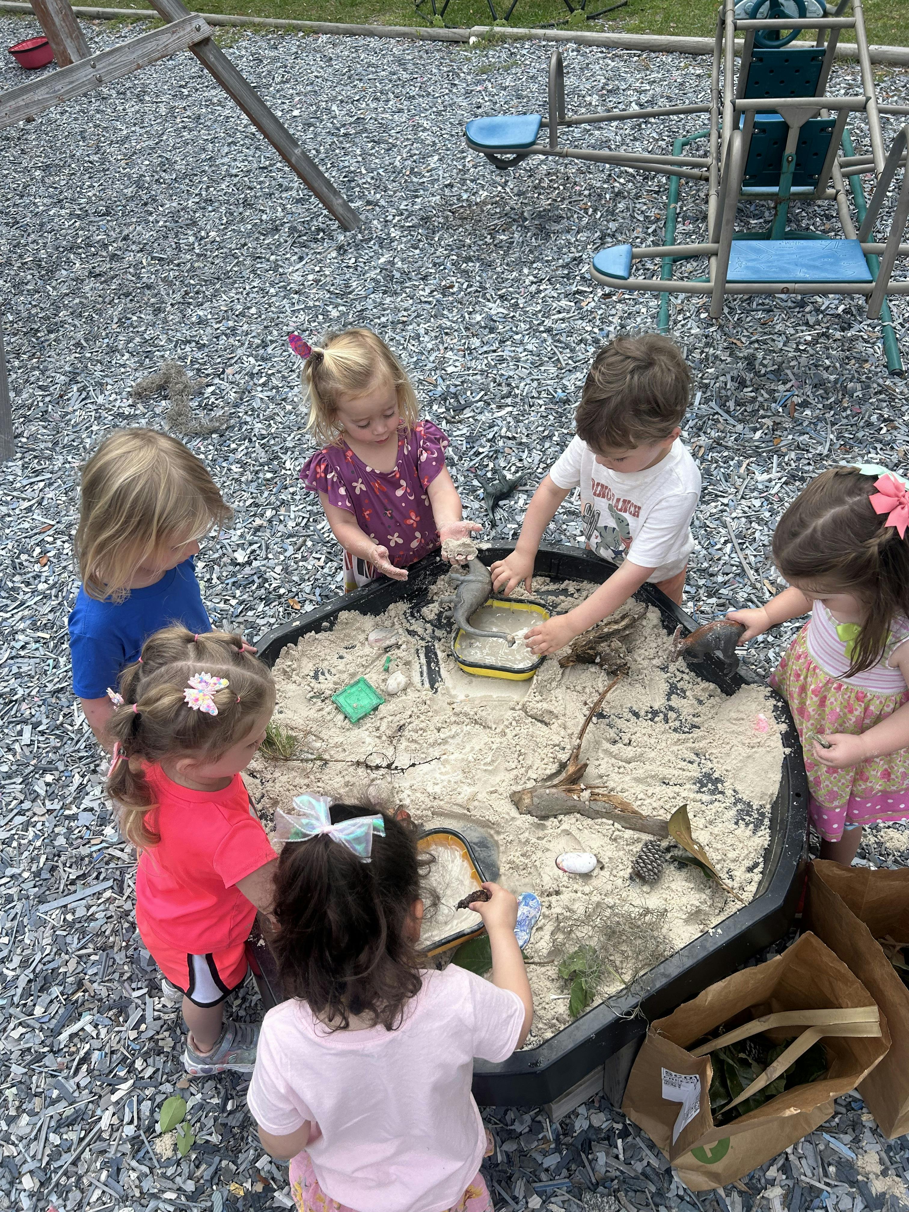 Children playing in a sand table outdoors