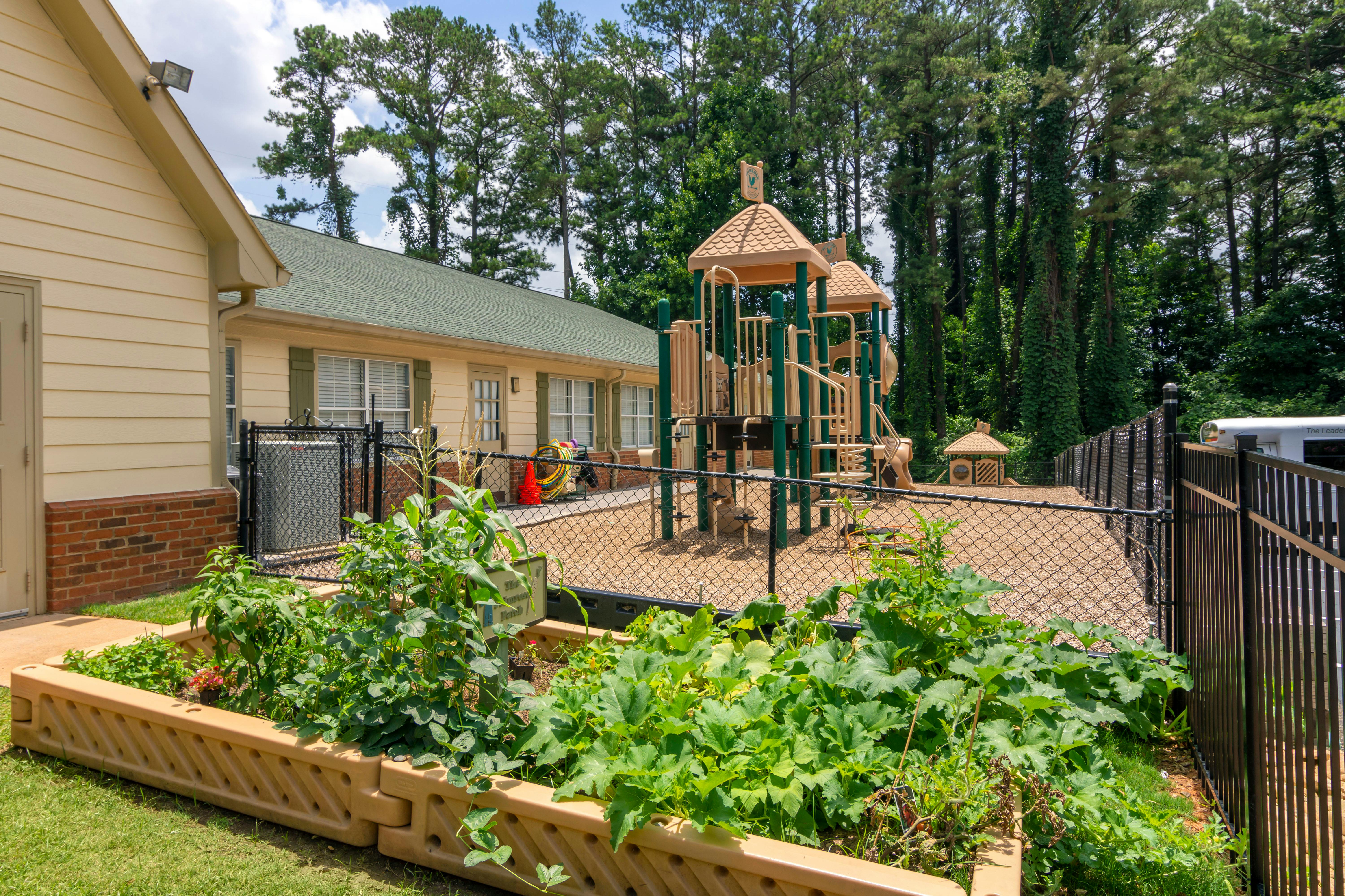 Playground area next to a building with a large garden bed in the foreground