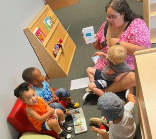 Adult reading to multiple children sitting on the floor