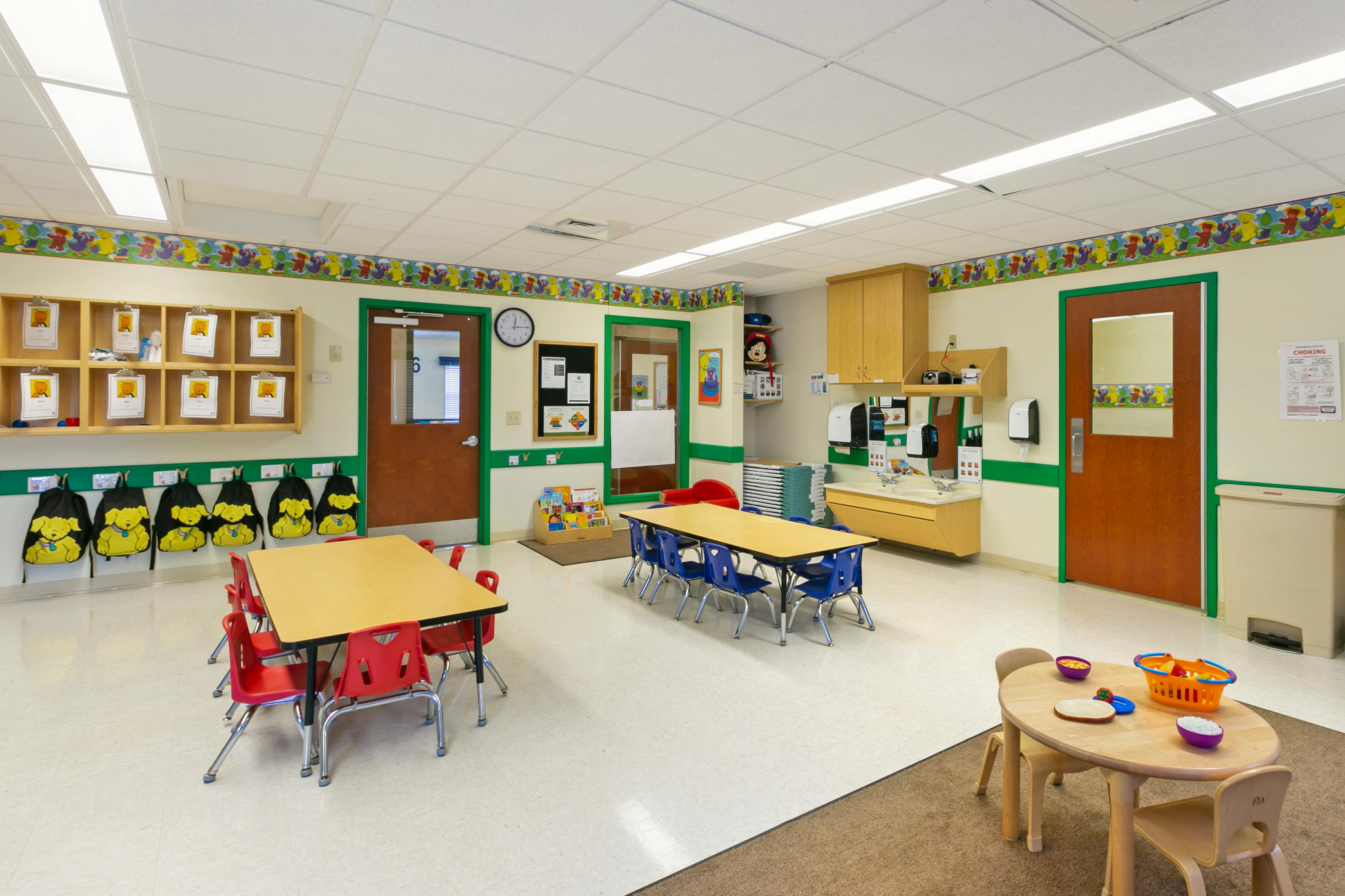 Classroom with child-sized tables and chairs, cubbies, and a sink
