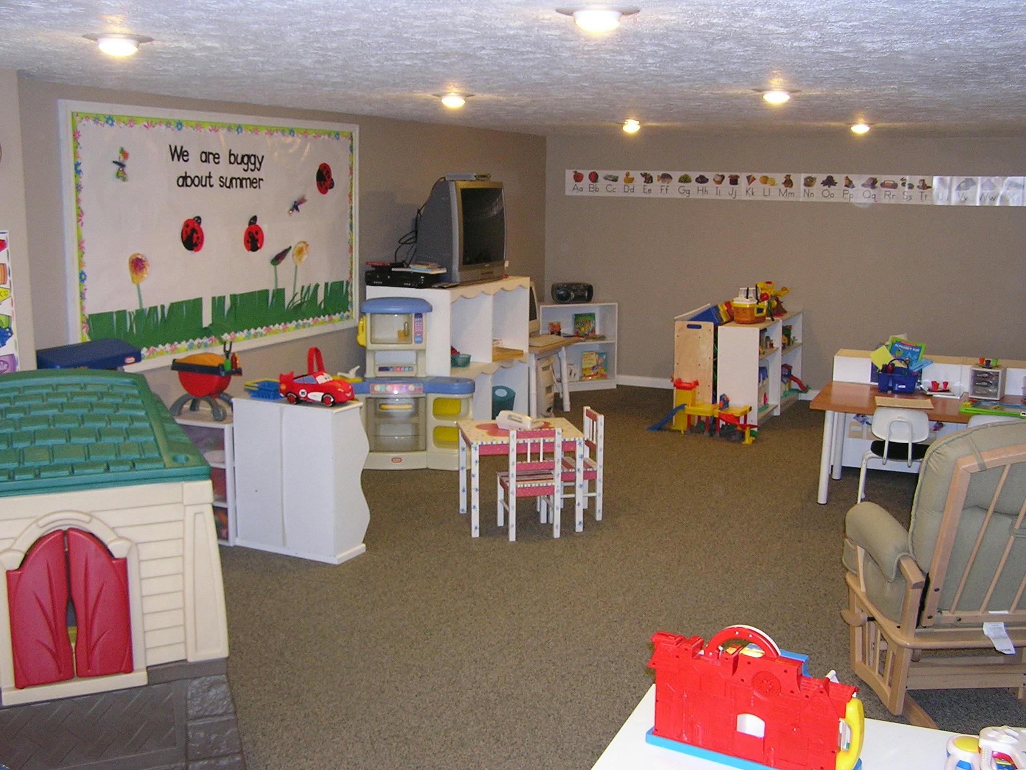 Playroom with small tables and chairs, toys, and a playhouse