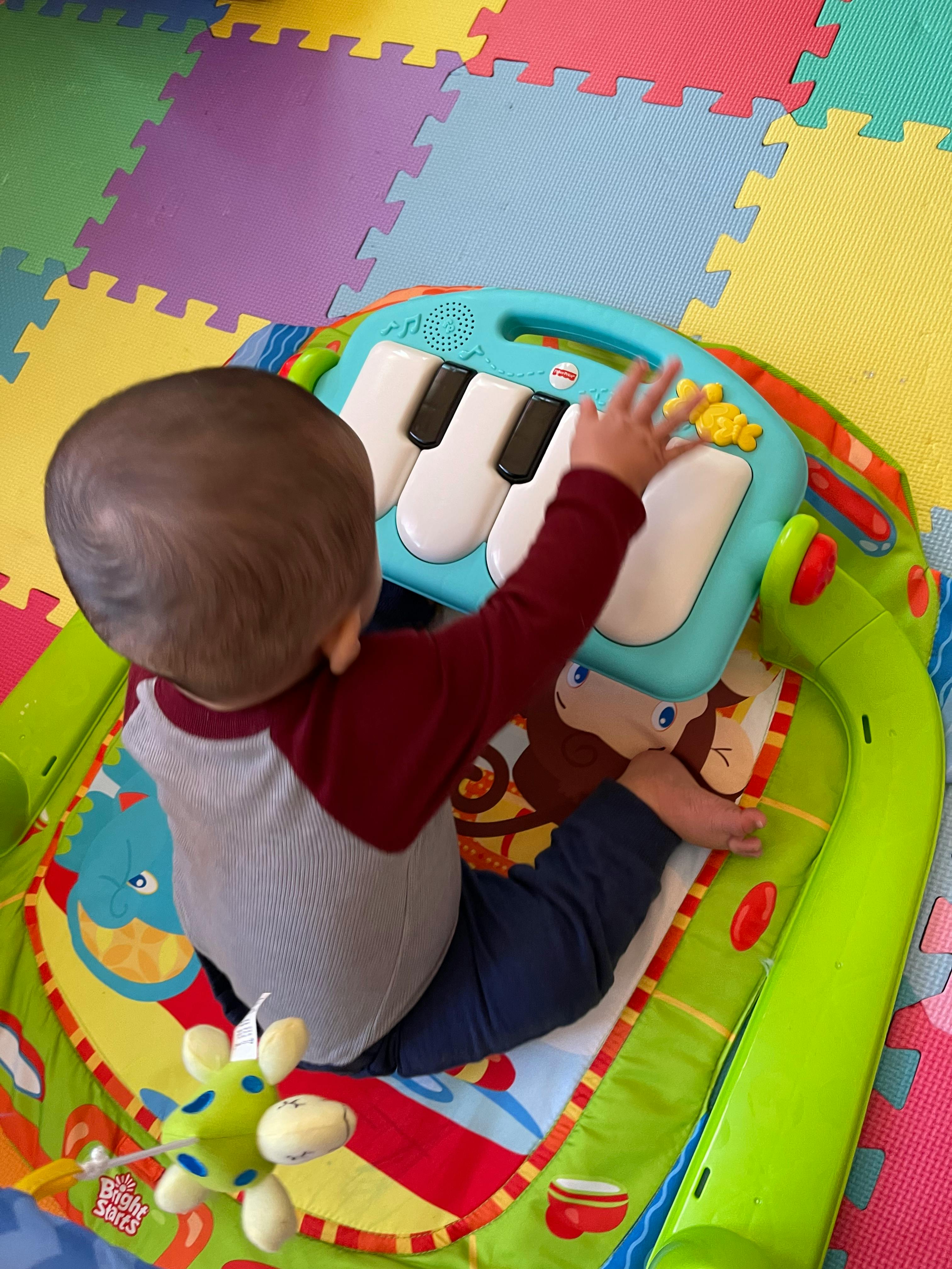 Child playing with a toy piano on a playmat