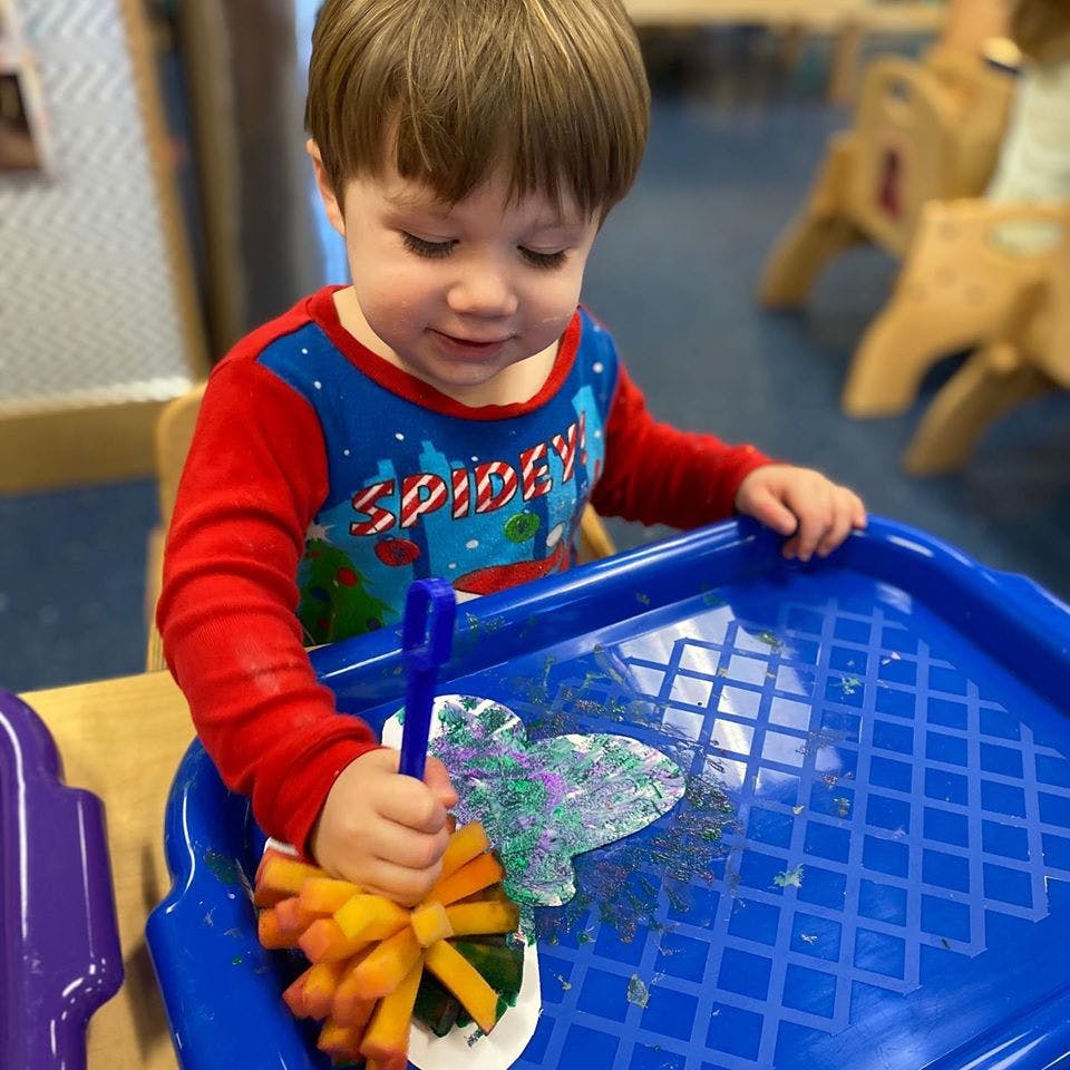 Child playing with a craft in a blue tray