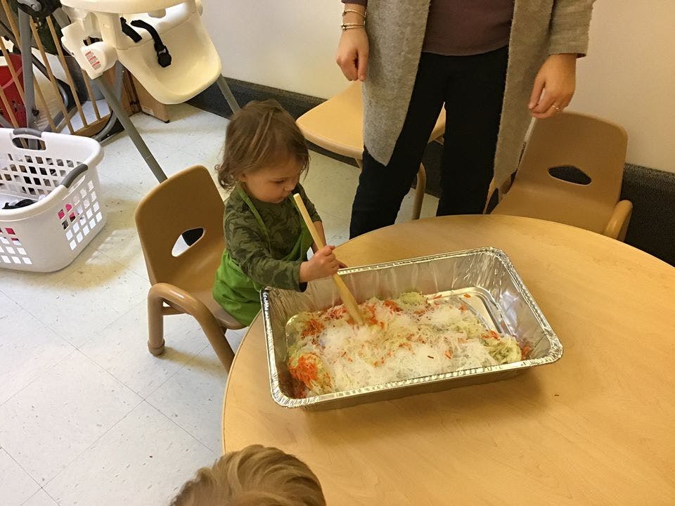 Child stirring contents of a foil pan on a table
