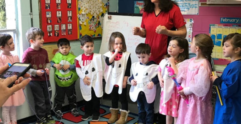 Adult and children in a classroom, some children wearing tooth costumes