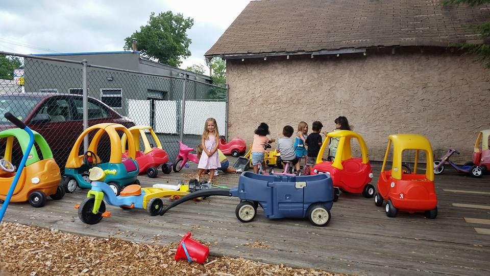 Children playing with toy cars and wagons outdoors