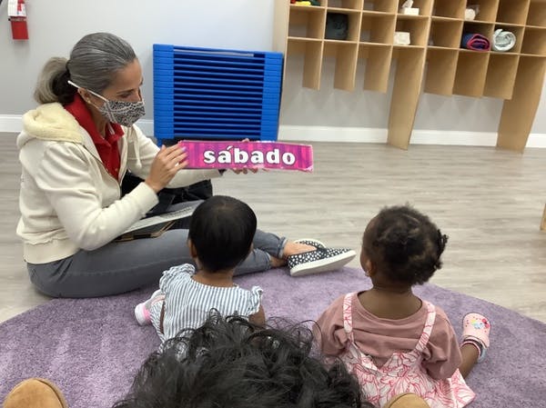 Person in mask holding a sign with "sábado" to children