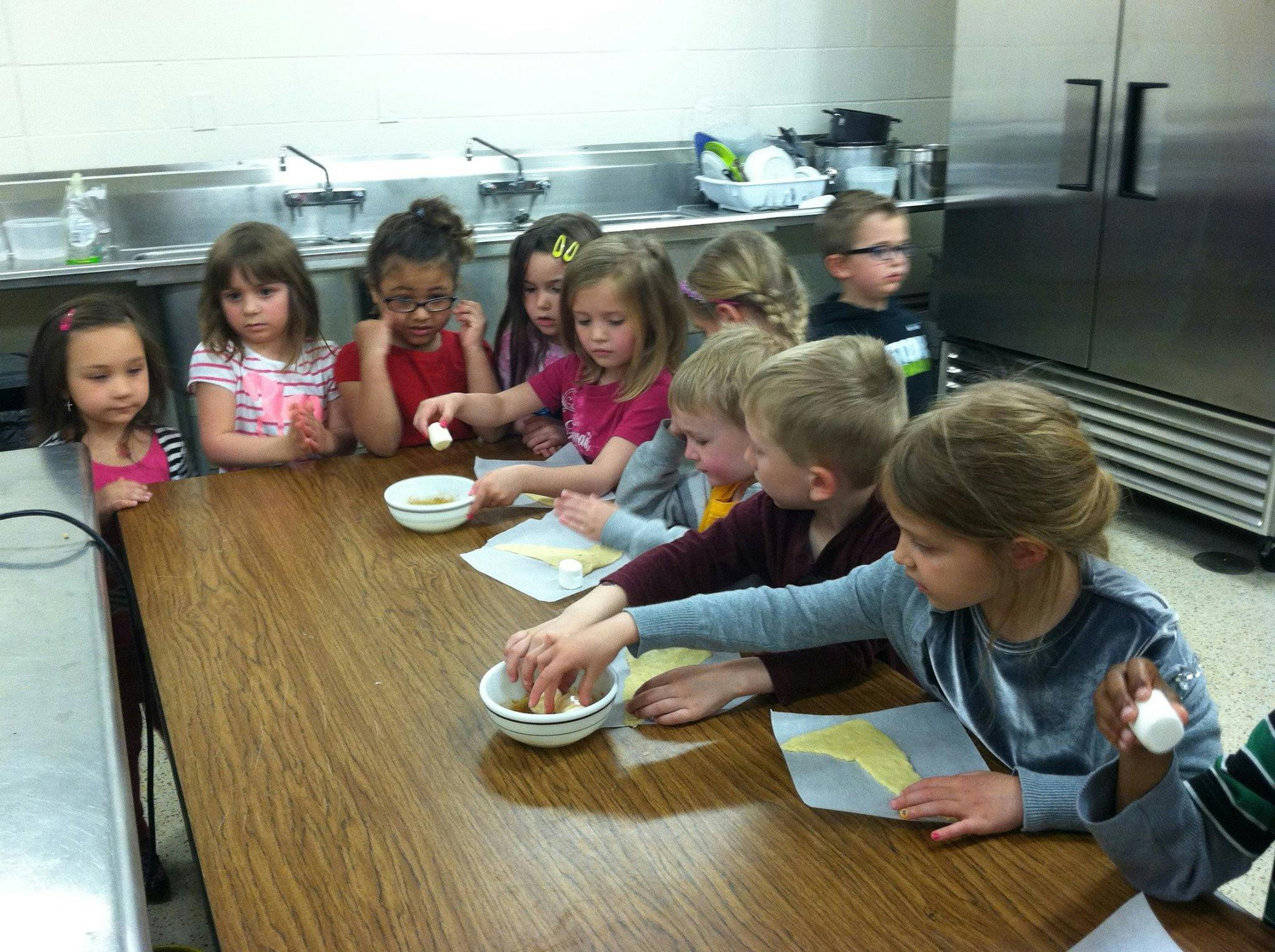 Children at a table with bowls and paper in a kitchen