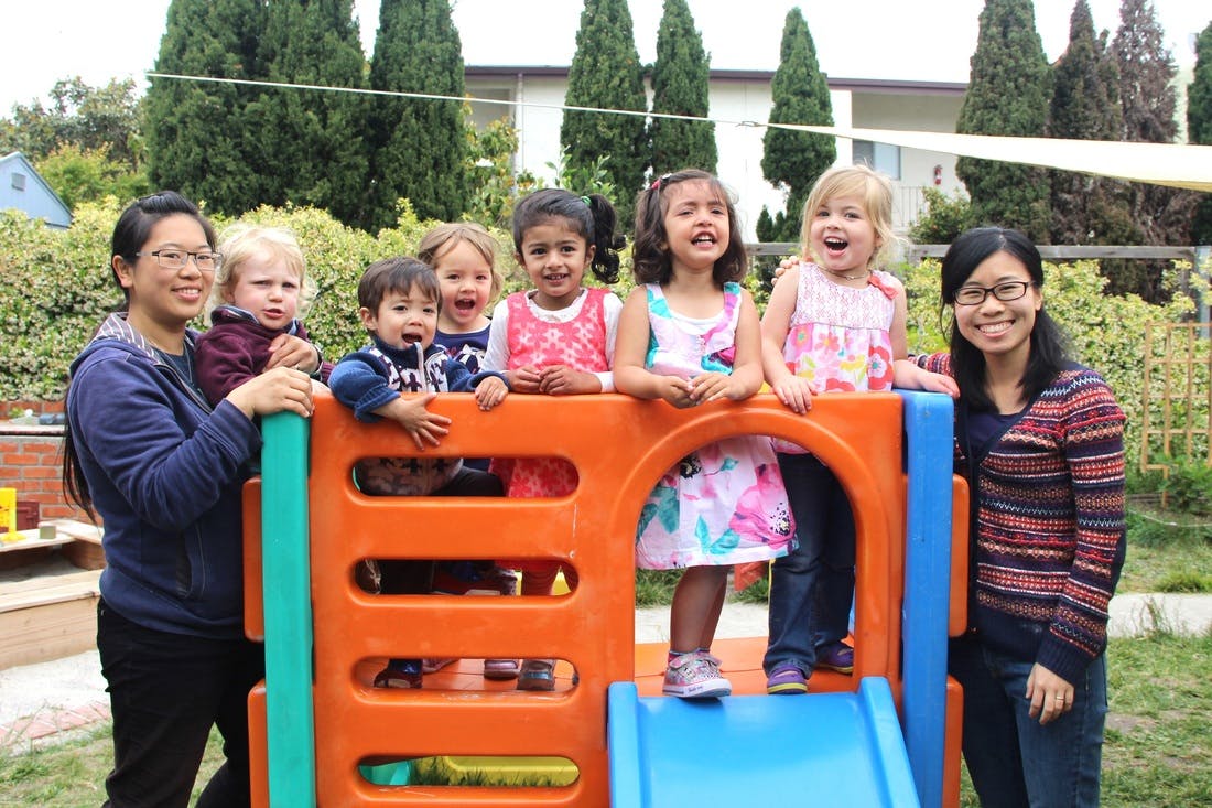 Two people and multiple children on a playground structure