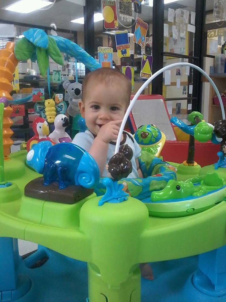 Child in a green and blue activity center with toys