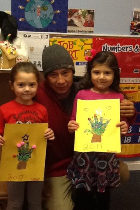 Person and two children holding up artwork with handprints