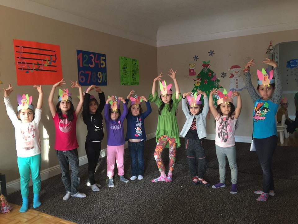 Group of children wearing paper crowns with hands raised