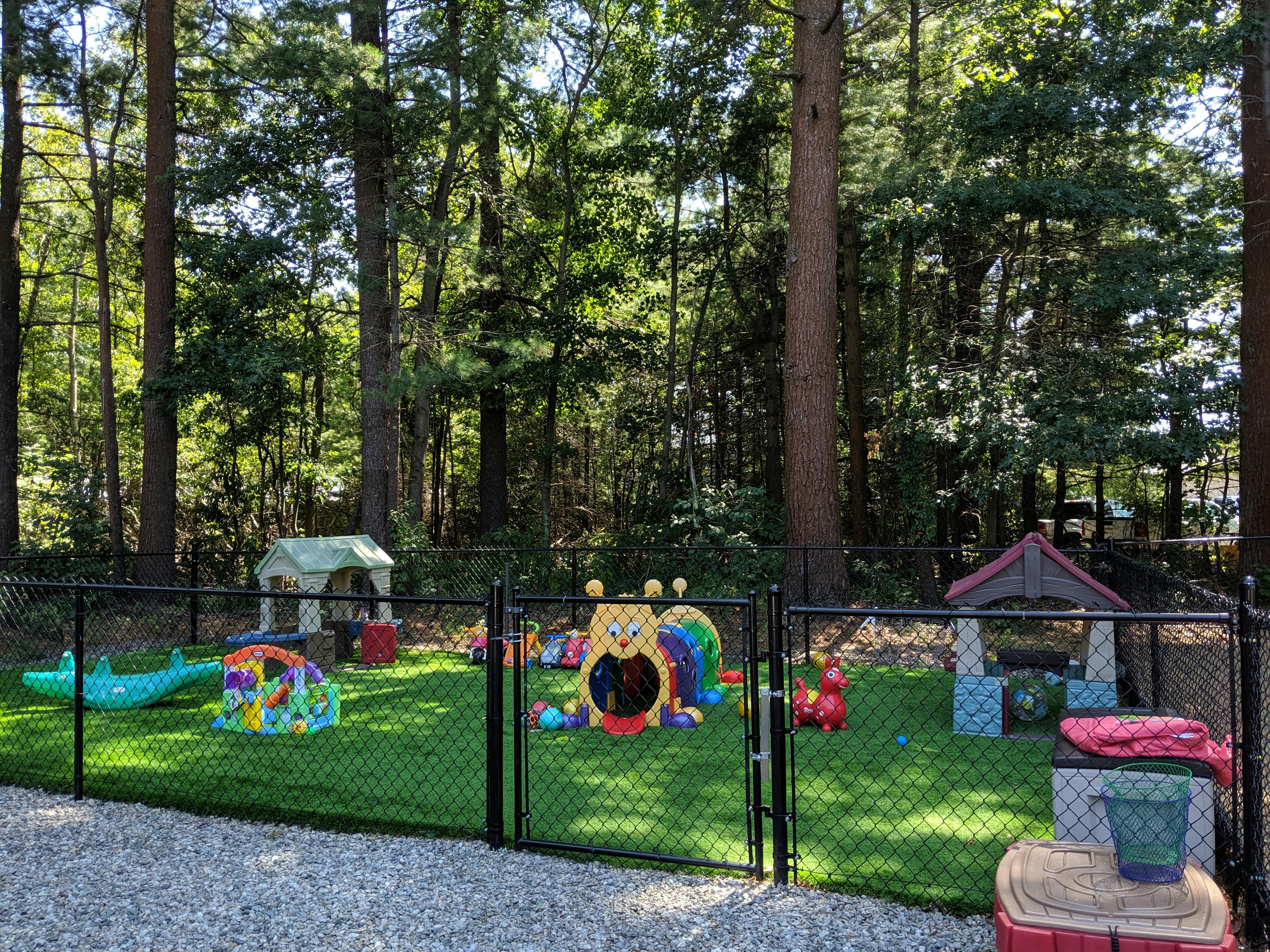 Fenced outdoor play area with various colorful toys and structures