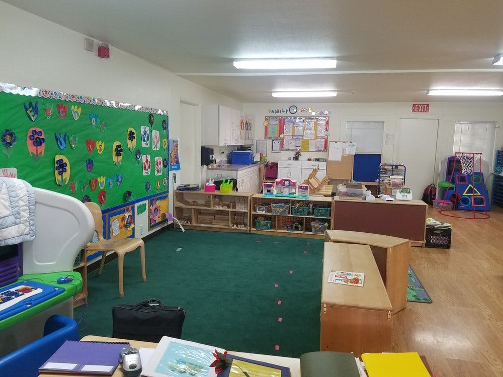 Classroom with green carpet, shelves, and a bulletin board