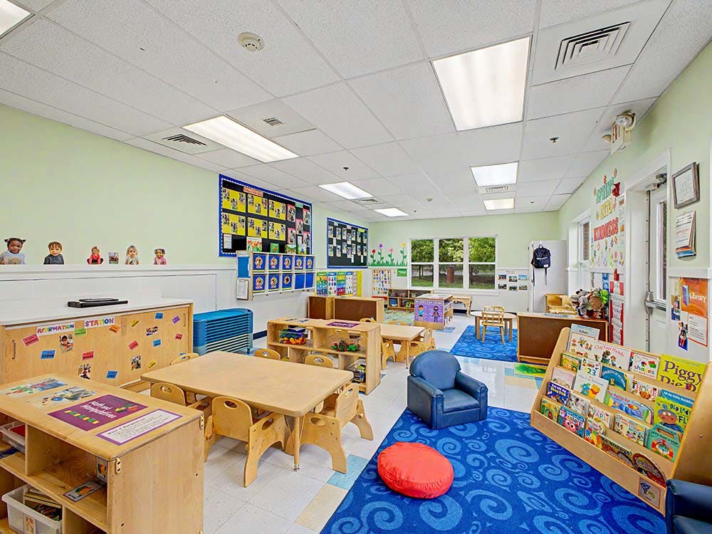 Colorful and organized empty preschool classroom with small tables and chairs