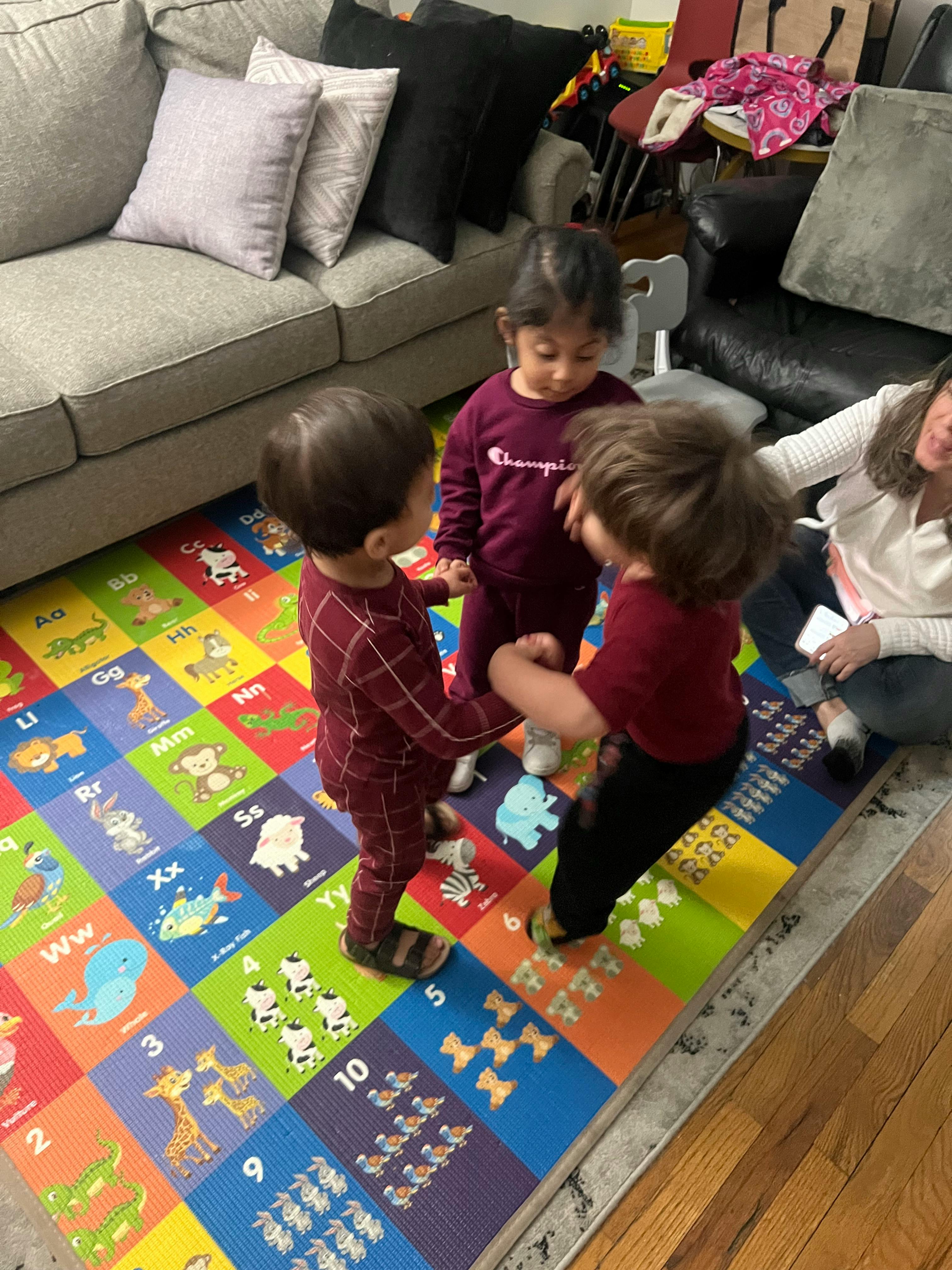 Three children playing on a colorful alphabet and numbers mat