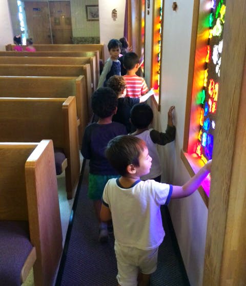 Children walking past stained glass windows in a church