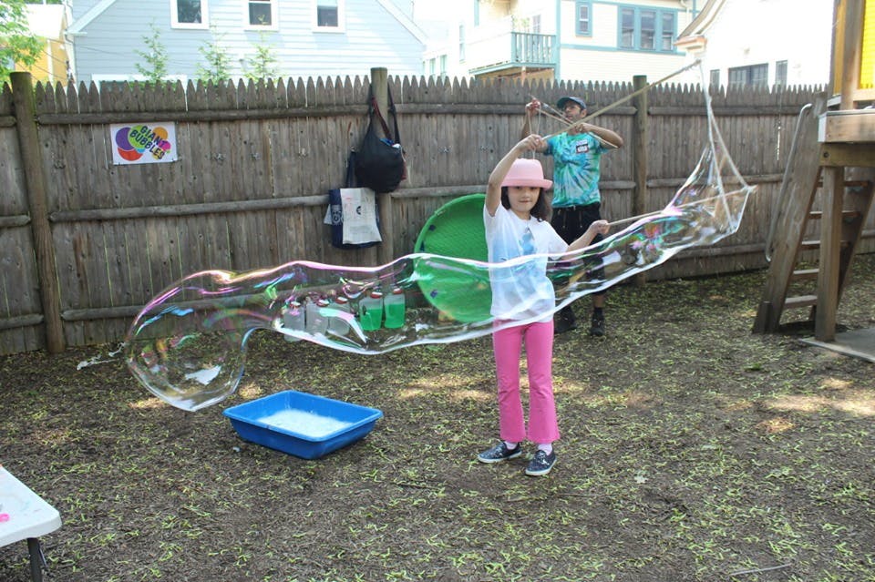 Child making a large bubble with a bubble wand