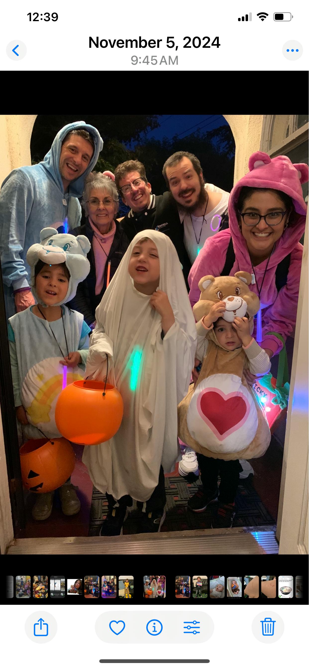 Group of people and children in Halloween costumes holding trick-or-treat buckets
