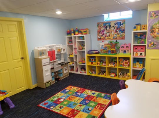 Playroom with toy shelves, play kitchen, and colorful rug