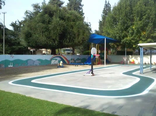 Outdoor playground with a basketball hoop and painted wall mural on track