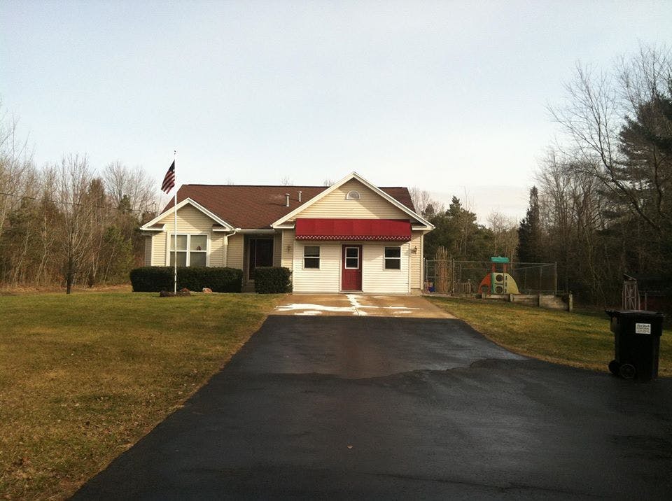 House with a red awning and a driveway leading to it
