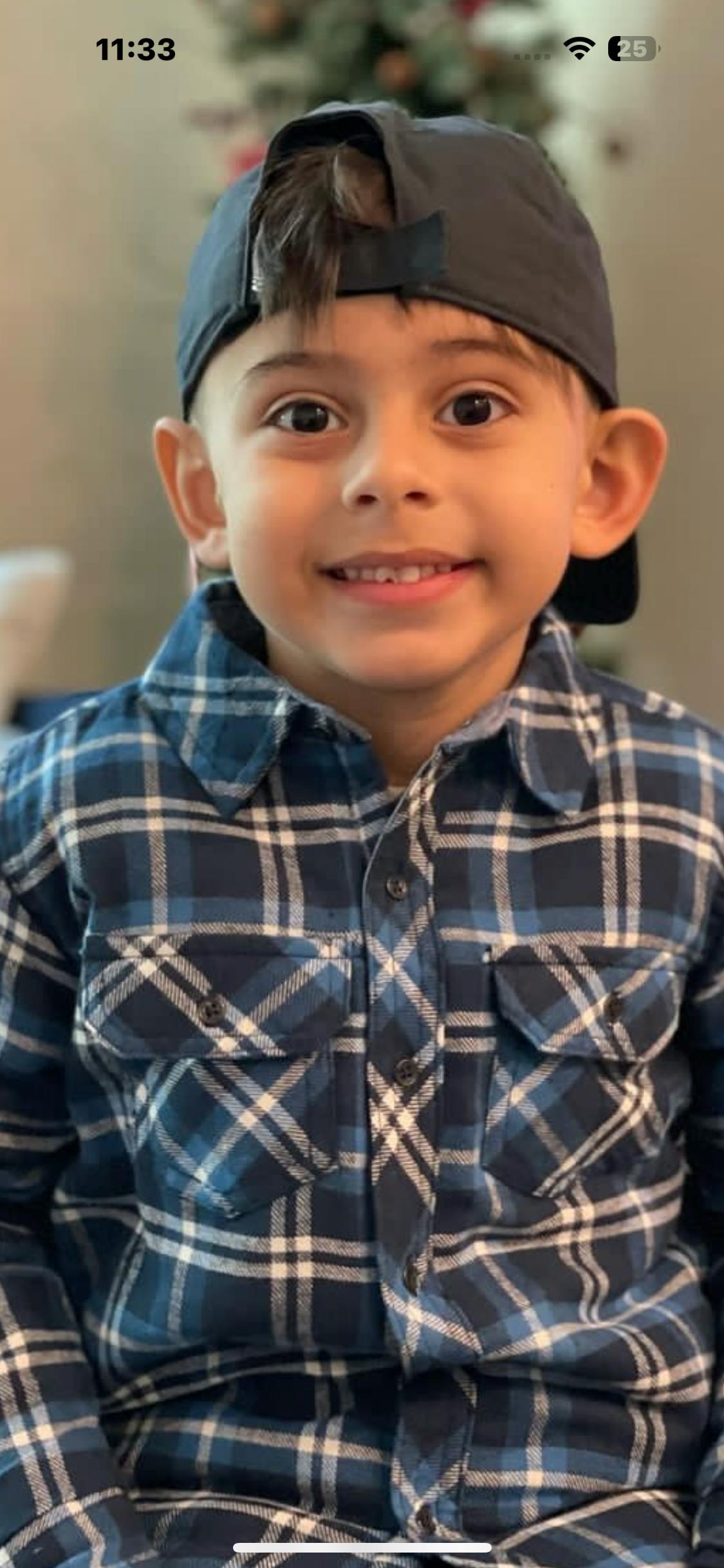 Child wearing a plaid shirt and a baseball cap