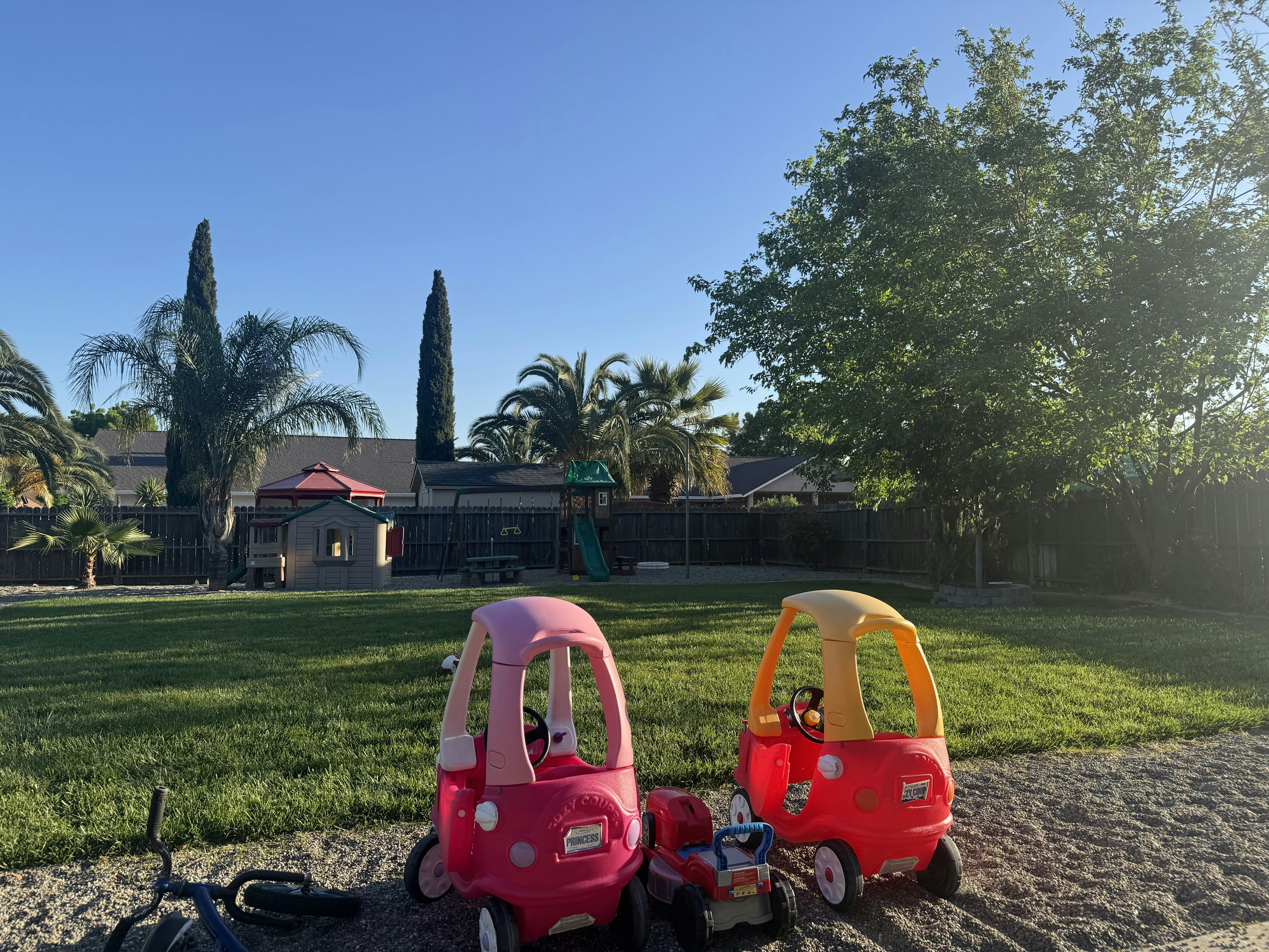 Toy cars in a backyard with a playground in the background