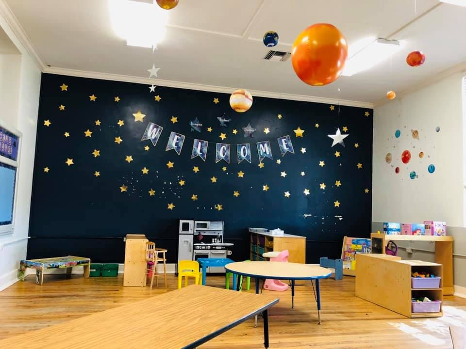 Classroom with a dark wall decorated with stars and a "Welcome" banner
