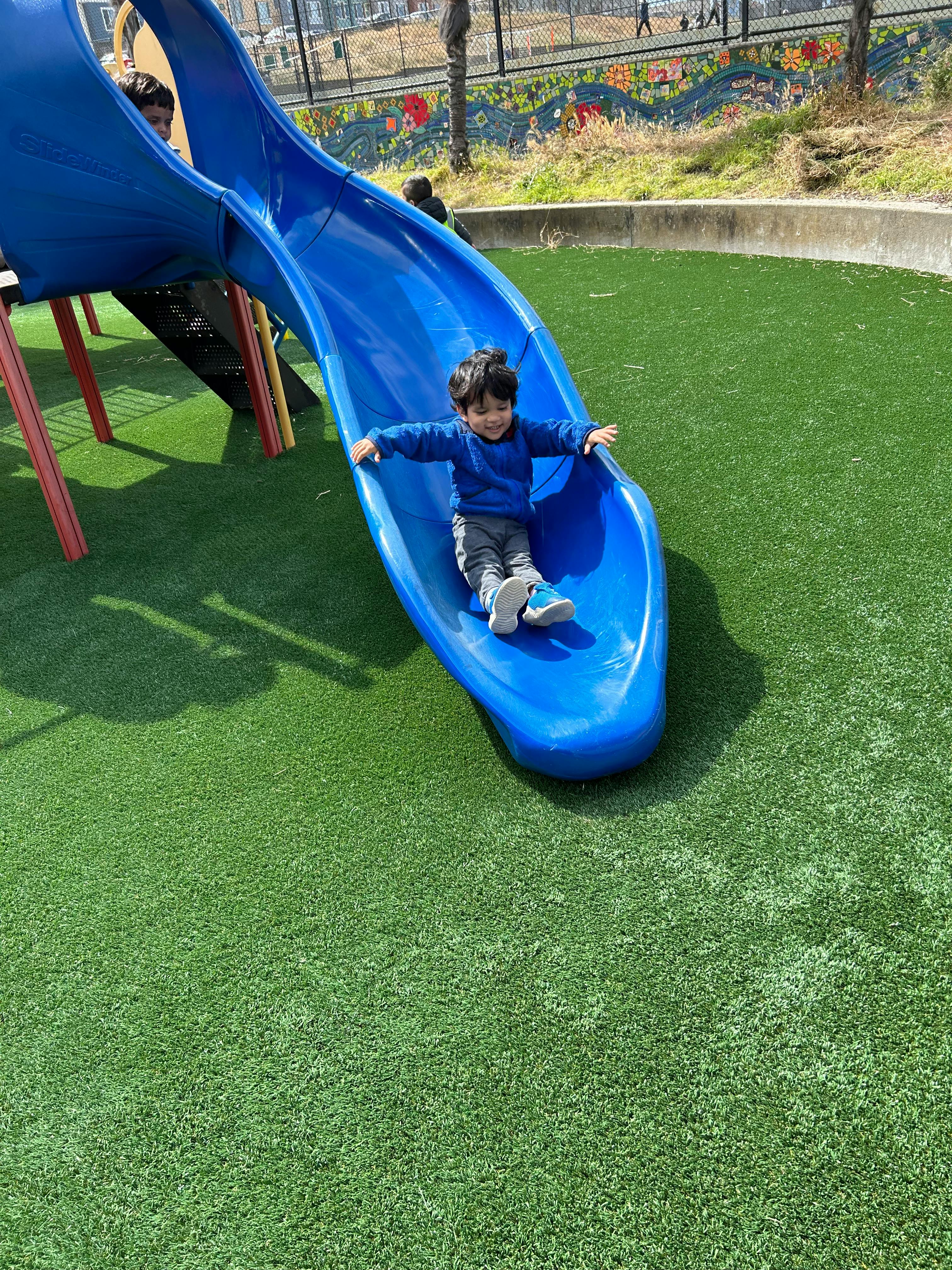 Child on a blue playground slide