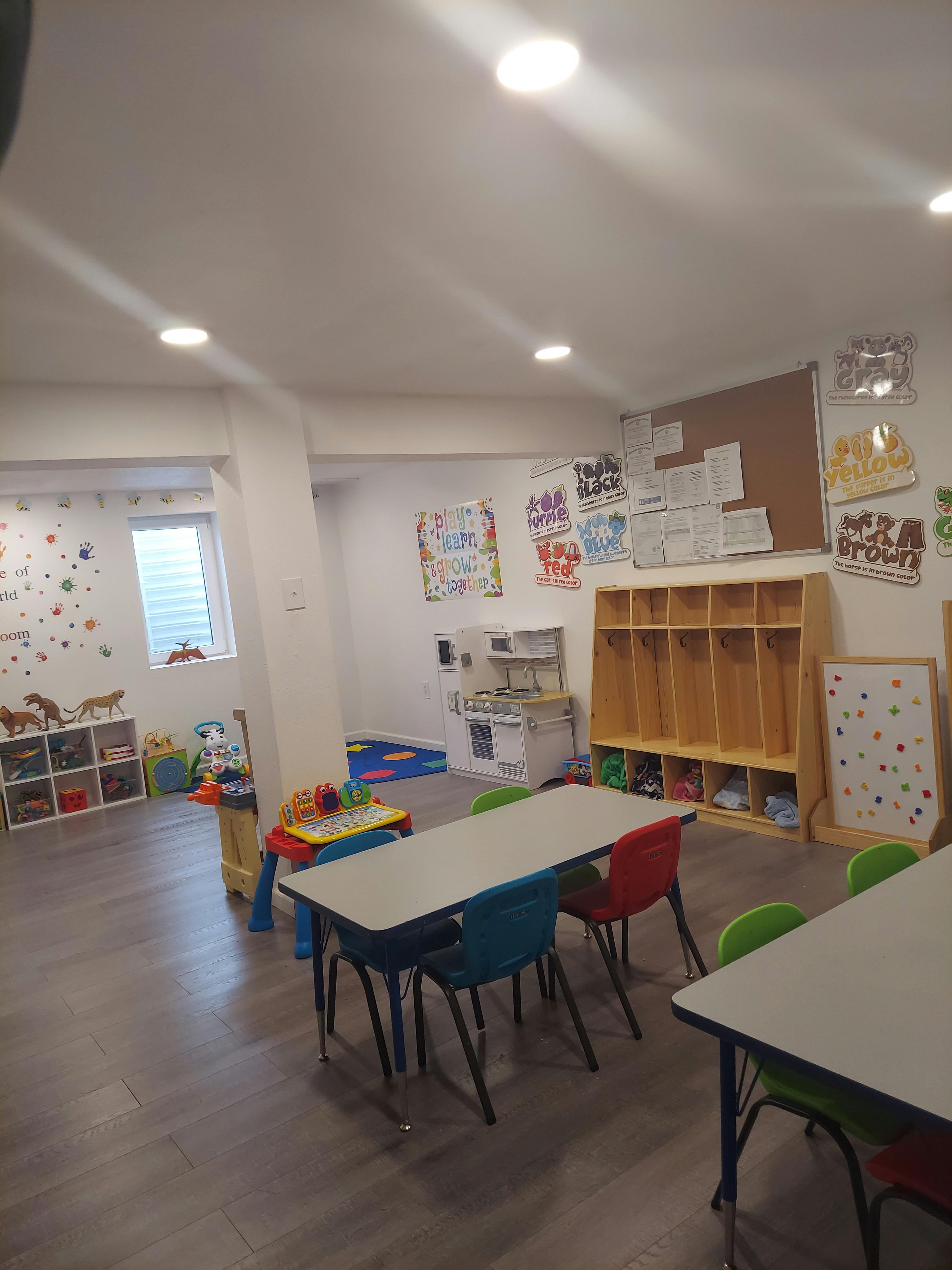 Classroom with small tables and chairs, cubbies, and play kitchen