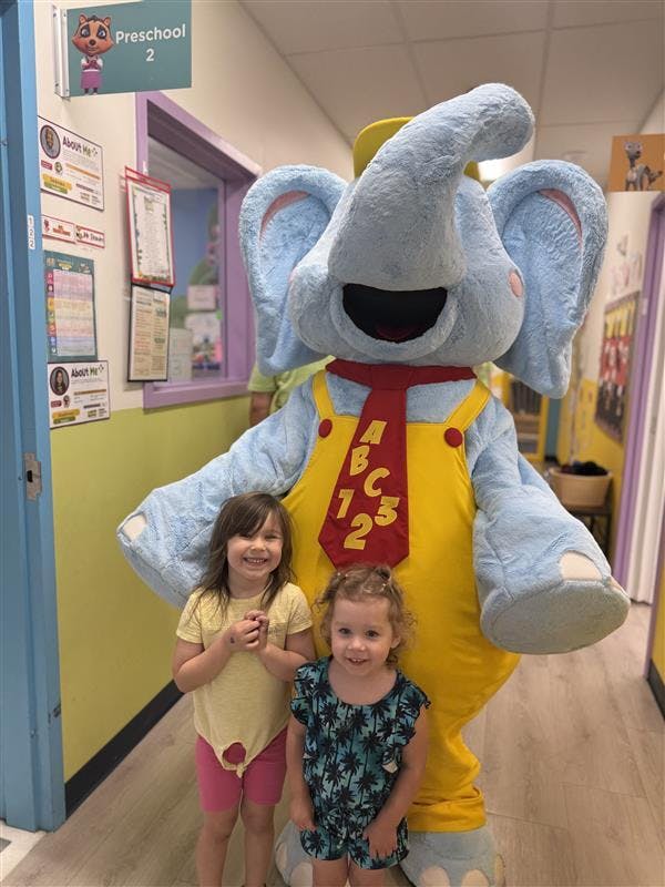 Two children standing with a person in an elephant costume