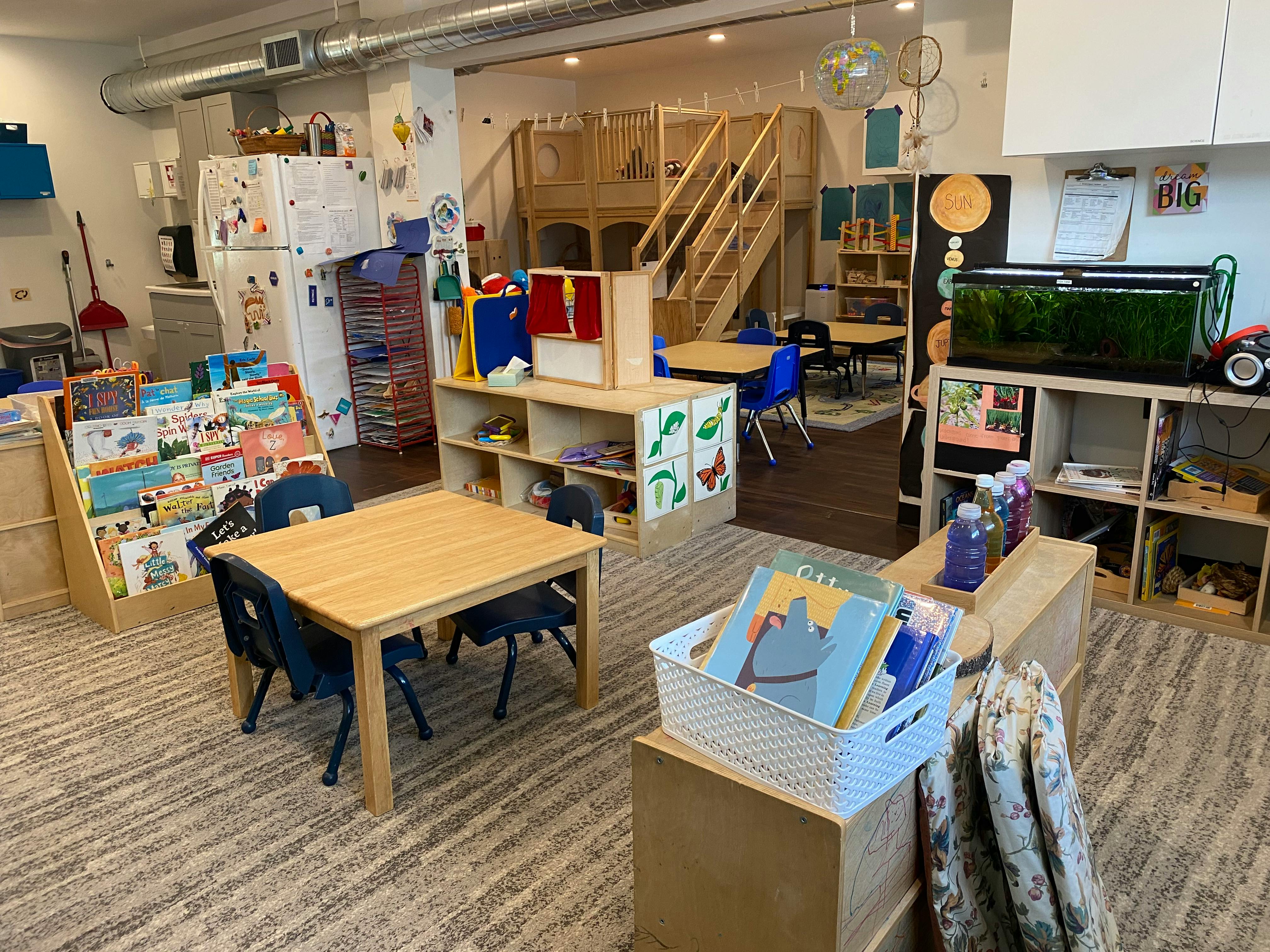 Classroom with small tables and chairs, bookshelves, and a fish tank