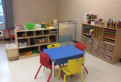 Classroom with small table and chairs, shelves with supplies