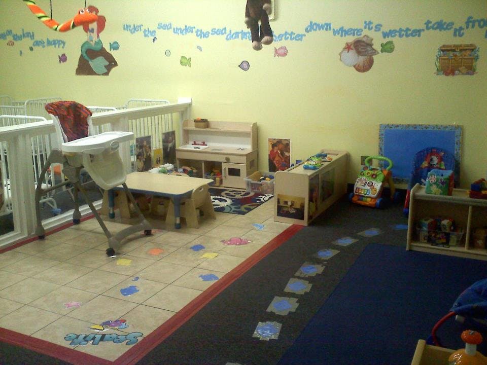Daycare room with cribs, high chair, and play area