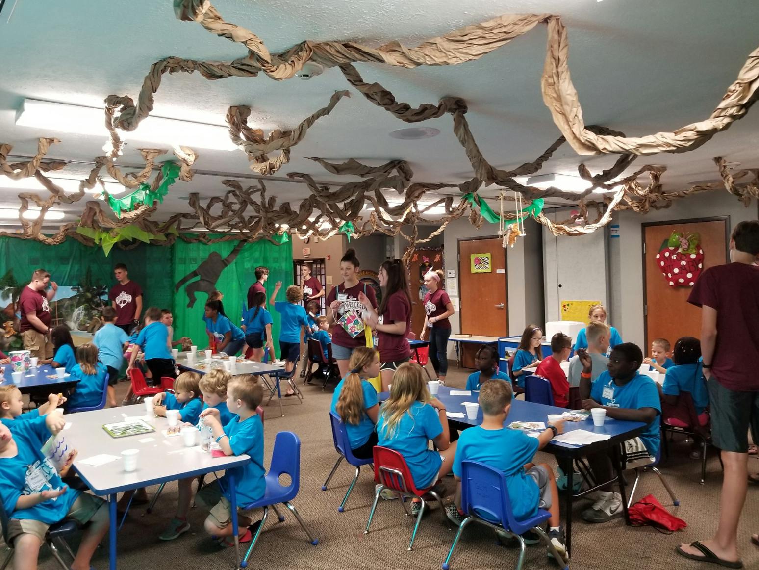 Children and adults in a decorated room with tables and chairs