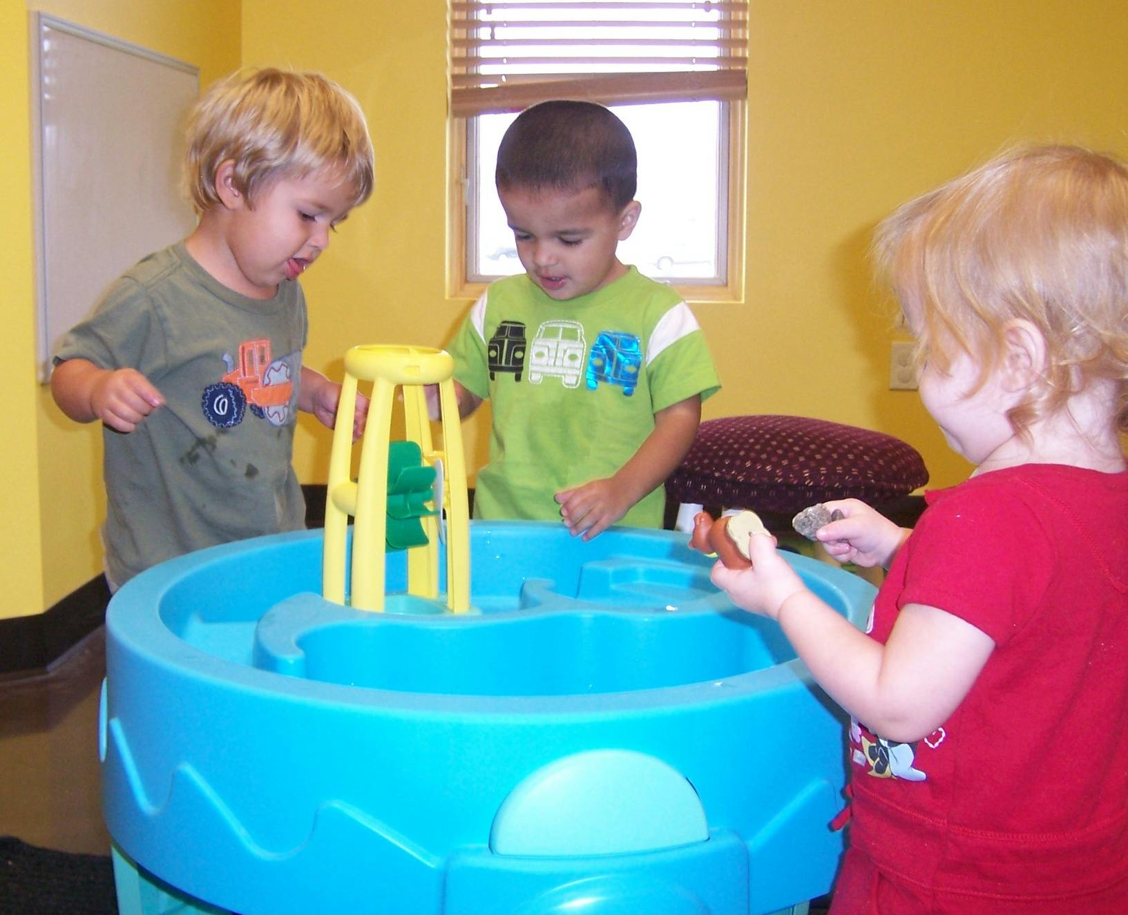 Three children playing with a water table