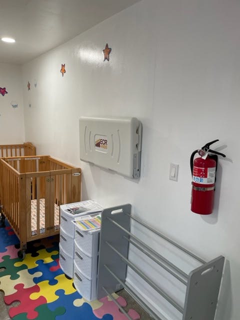 Nursery room with cribs, changing station, and fire extinguisher