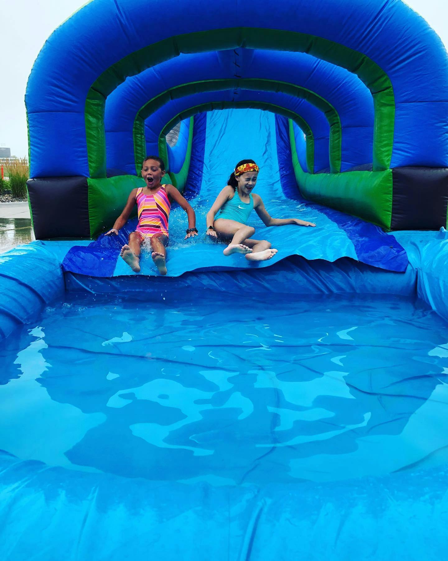 Two children sliding down an inflatable water slide