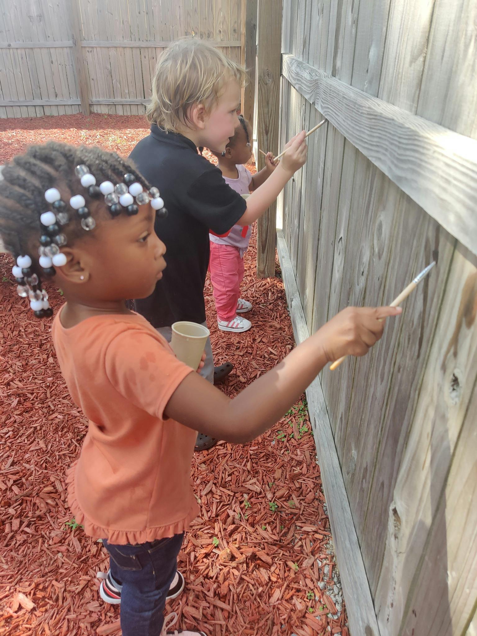 Children painting a wooden fence