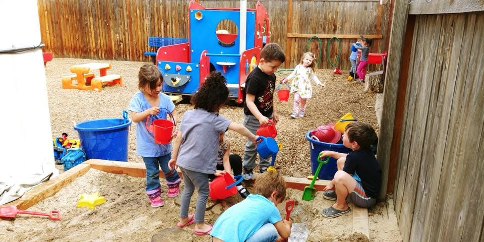 Children playing in a sandbox with toys