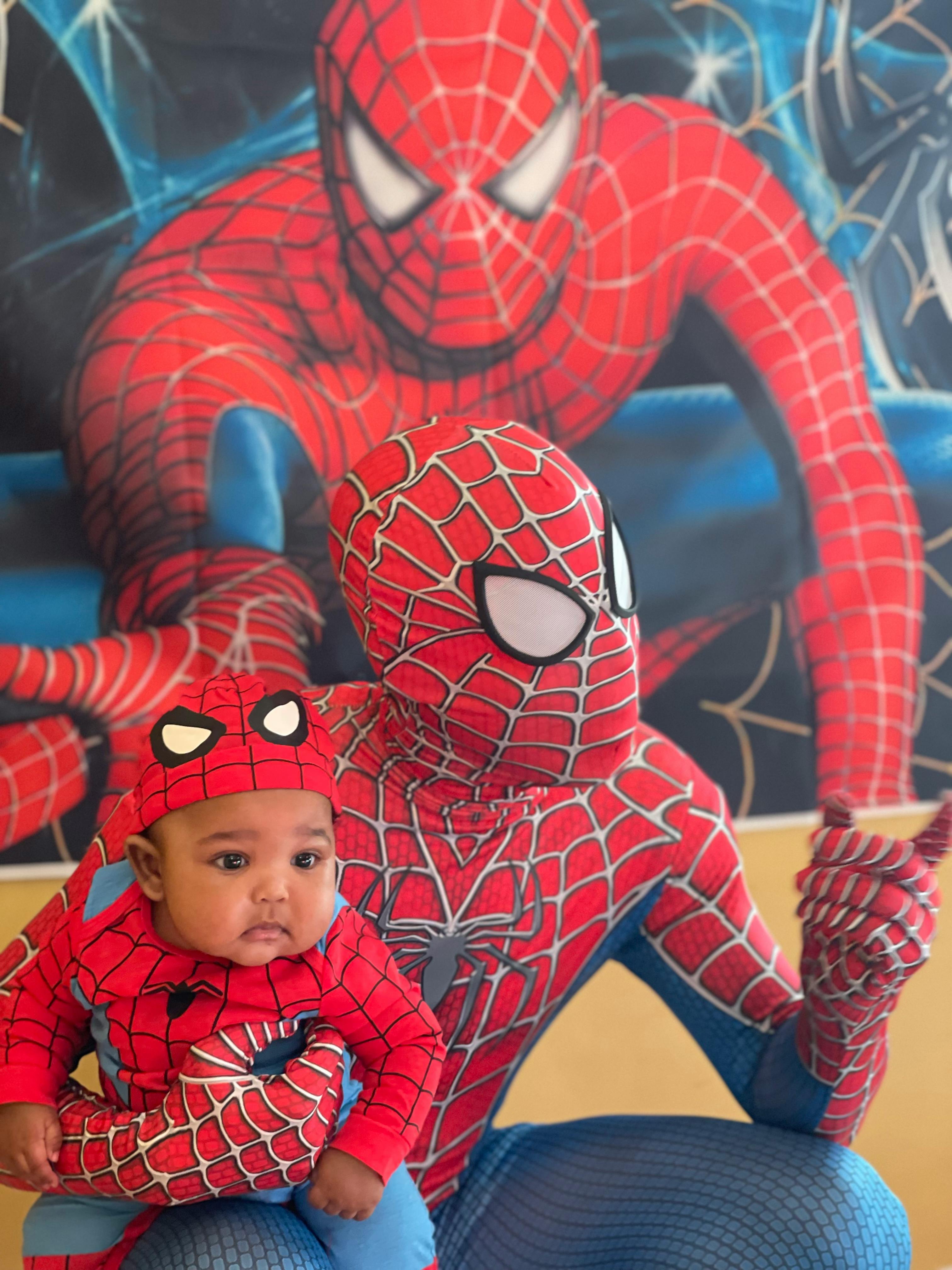 Person in a Spider-Man costume holding a child in a Spider-Man costume